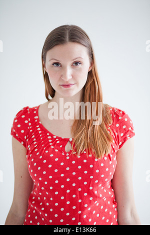 Studio portrait of thoughtful looking attractive woman wearing red spotty blouse Stock Photo
