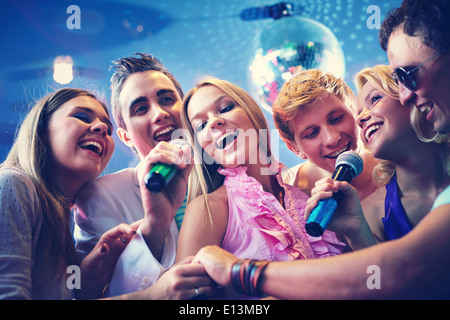 Portrait of joyous guys and girls singing at party together Stock Photo