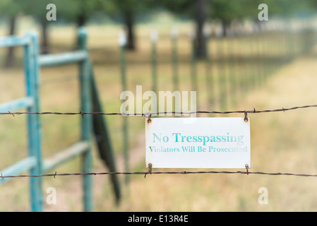 No tresspassing sign attached on a barbed wire fence Stock Photo