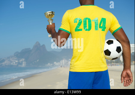 Champion Brazilian soccer player holding trophy and football in 2014 shirt Ipanema Beach Rio de Janeiro Brazil Stock Photo