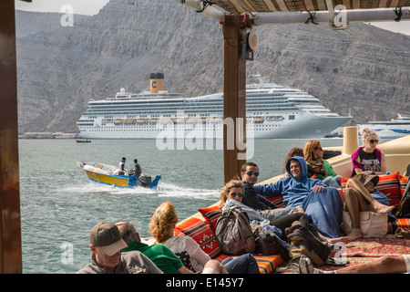 Oman, Khasab, Harbor, Iranian smugglers bringing goods back to Iran with small boats. Tourists on bow. Costa Fortuna cruise ship Stock Photo