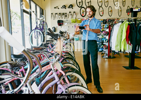 Caucasian businessman taking pictures in bicycle shop
