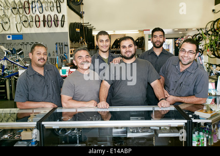 Mechanics smiling in bicycle repair shop Stock Photo