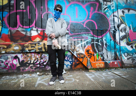 Caucasian teenage boy standing by graffiti wall Stock Photo