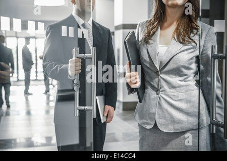Businessman holding door open for female colleague Stock Photo
