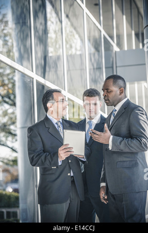 Businessmen using digital tablet outside office Stock Photo