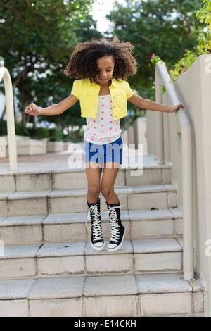 Mixed race girl jumping on steps