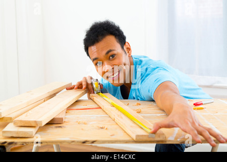 Mixed race carpenter measuring wood with tape measure Stock Photo