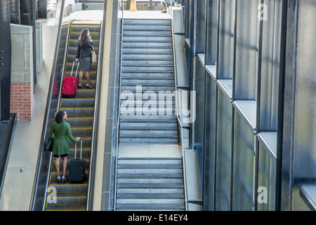 Businesswomen riding escalator Stock Photo