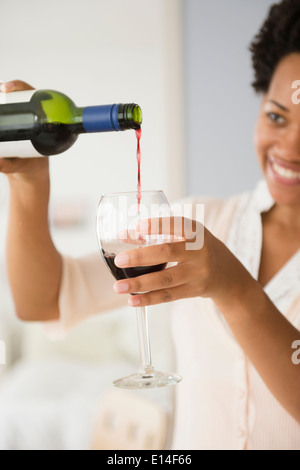 Black woman pouring glass of red wine Stock Photo
