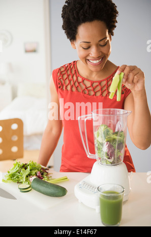Black woman making green smoothies in blender