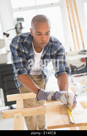 Black carpenter measuring wood in shop Stock Photo