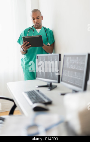 Black doctor using digital tablet in office Stock Photo