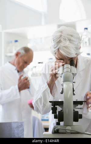 Senior Caucasian scientist using microscope in lab Stock Photo