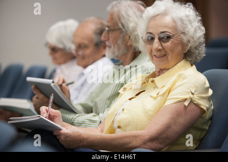 Senior Caucasian students taking notes in classroom Stock Photo