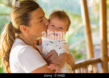 Caucasian mother kissing baby's cheek