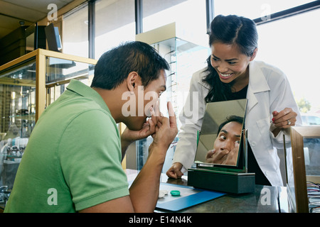 Optometrist helping patient with contacts in office Stock Photo