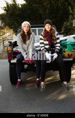 Women sitting together in truck bed Stock Photo