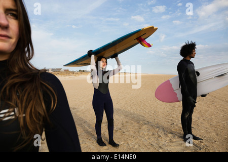 Surfers carrying boards on beach Stock Photo