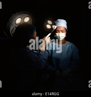 Caucasian nurse wiping sweat from surgeon's brow Stock Photo