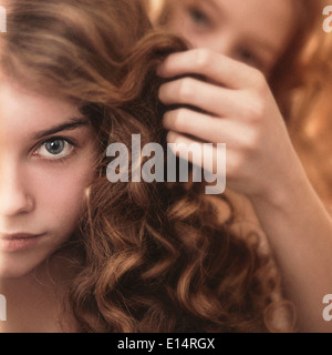Caucasian girl braiding friend's hair Stock Photo