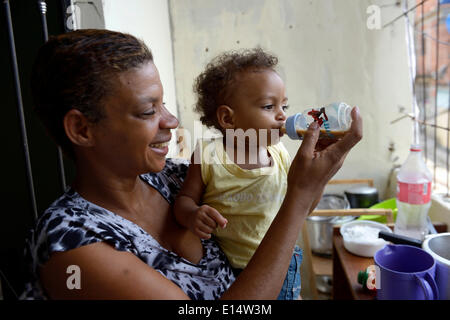 Woman, 38, in a favela, giving her son, 1 year, a bottle of drinking chocolate, Senador Camara favela, Rio de Janeiro Stock Photo