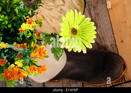Silk flowers in a rubber boot garden. Stock Photo