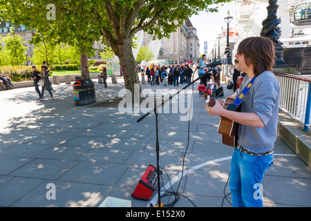 Busker playing acoustic guitar on the London embankment Stock Photo