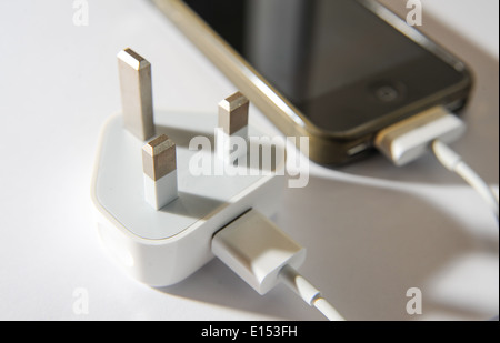 Apple iPhone 4s and charger In the UK there have been a spate of accidents involving fake chargers being used with mobile phones Stock Photo
