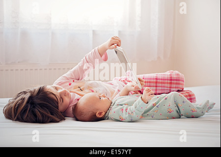 Sisters together lying and watching tablet Stock Photo