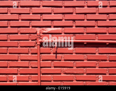 Red brick wall with water pipes and shut-off valve open. Stock Photo