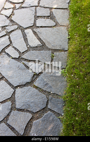 Garden path and stone in grassy green lawn Stock Photo