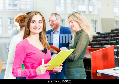 College students asking professor in university auditorium after lecture Stock Photo
