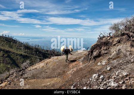 Miner carrying a heavy load of sulphur at the Kawah Ijen volcanic crater, Java, Indonesia Stock Photo
