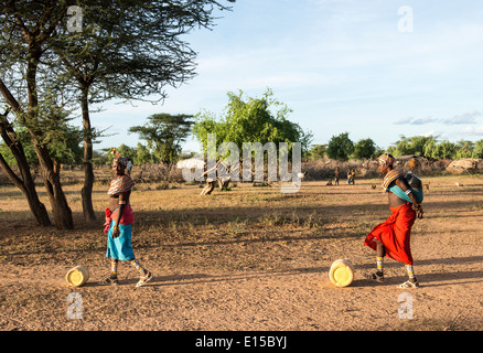 Samburu girls rolling jericans filled with water from the well back to their village. Stock Photo