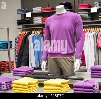 Fashionable clothing on hangers in shop Stock Photo