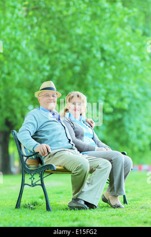 Mature man and woman relaxing in park seated on bench Stock Photo