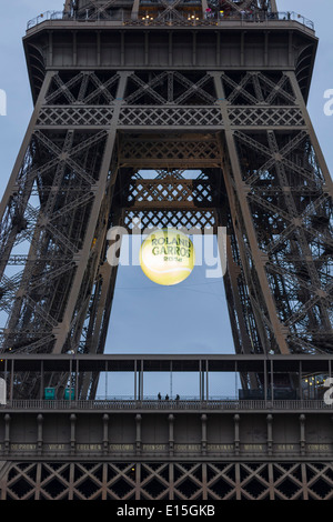 Eiffel Tower at sunset with a giant, illuminated tennis ball hanging over the first platform to promote the 2014 French Open.