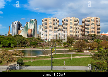 City park with small pond, green lawns and walkways and modern residential buildings on background in Valencia, Spain. Stock Photo