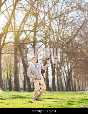 Senior man playing air guitar in the park Stock Photo