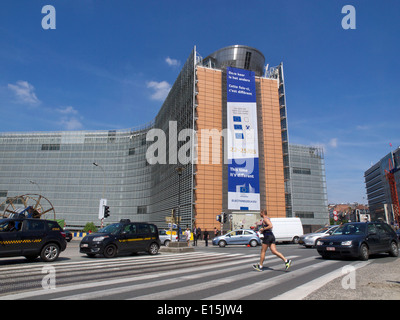 European Commission berlaymont building with runner crossing the street and parked taxis, Brussels, Belgium