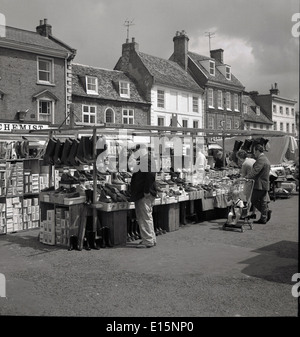 1950s historical picture of shoppers browsing a market stall selling Warkton shoes in the square at Newark on Trent, England. Stock Photo