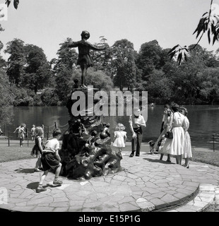 1950s. Historical picture of children with parents at bronze statue of Peter Pan by author J. M . Barrie, Kensington Gardens. Stock Photo