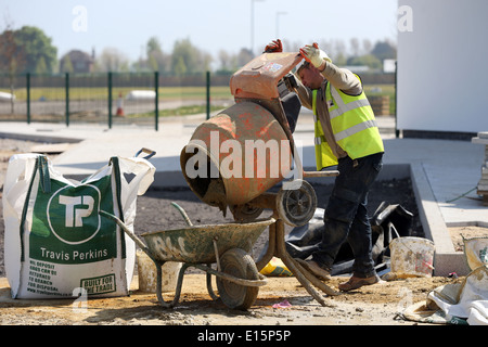 Tradesman workman cement mixer pouring cement into a wheel