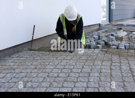 Tradesman workman building site laying paving slabs cobblestones Stock Photo