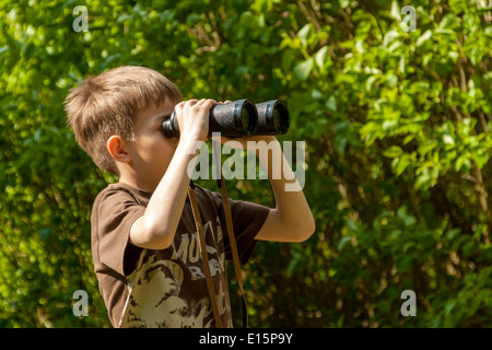 Boy watching birds through binoculars in a forest Stock Photo
