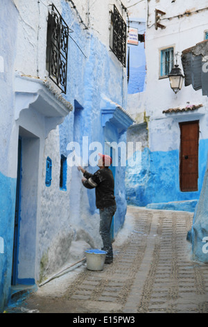 Moroccan man painting the streets blue in Chefchaouen Morocco Stock Photo