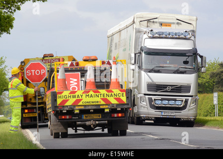 construction worker using lollipop stop - go sign to control traffic at roadworks united kingdom Stock Photo