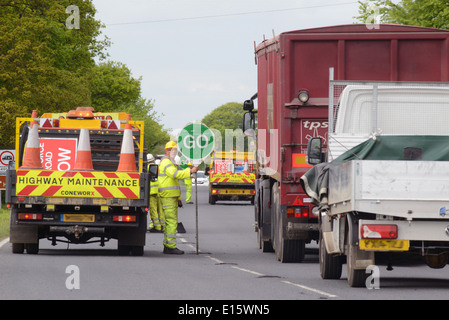 construction worker using lollipop stop - go sign to control traffic at roadworks united kingdom Stock Photo