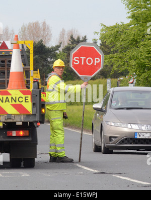 construction worker using lollipop stop - go sign to control traffic at roadworks united kingdom Stock Photo